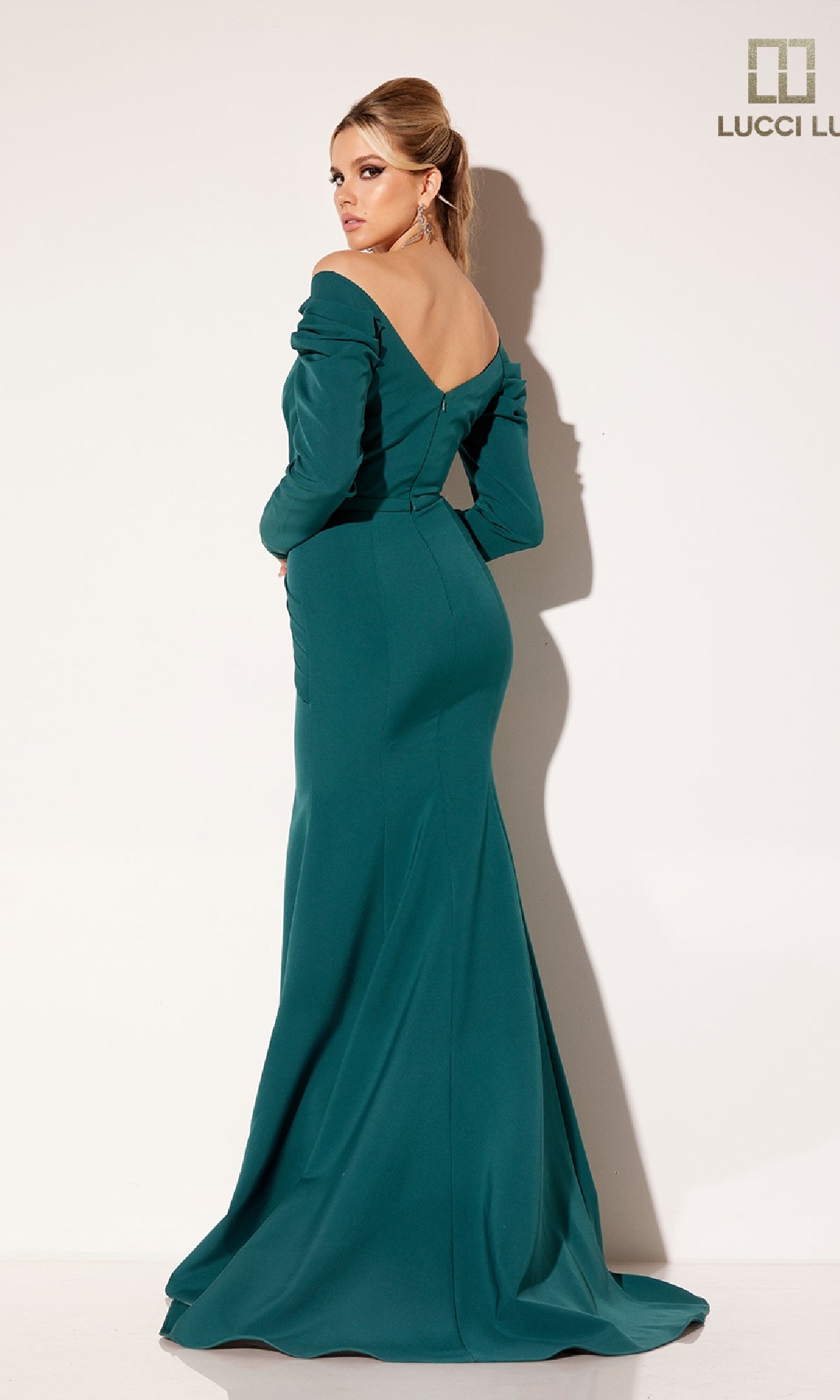 A woman models the Lucci Lu C8102, a fitted teal formal dress with long sleeves, off-the-shoulder neckline, and floor-length hem against a plain white background.